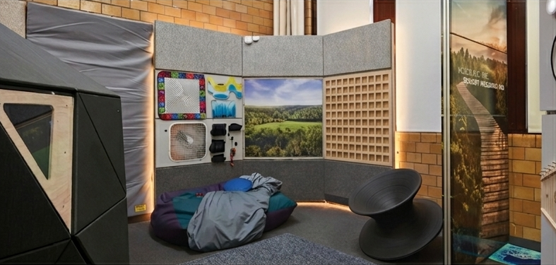 Respite Zone showing beanbag with weighted blanket, fidget wall components, and nature projection